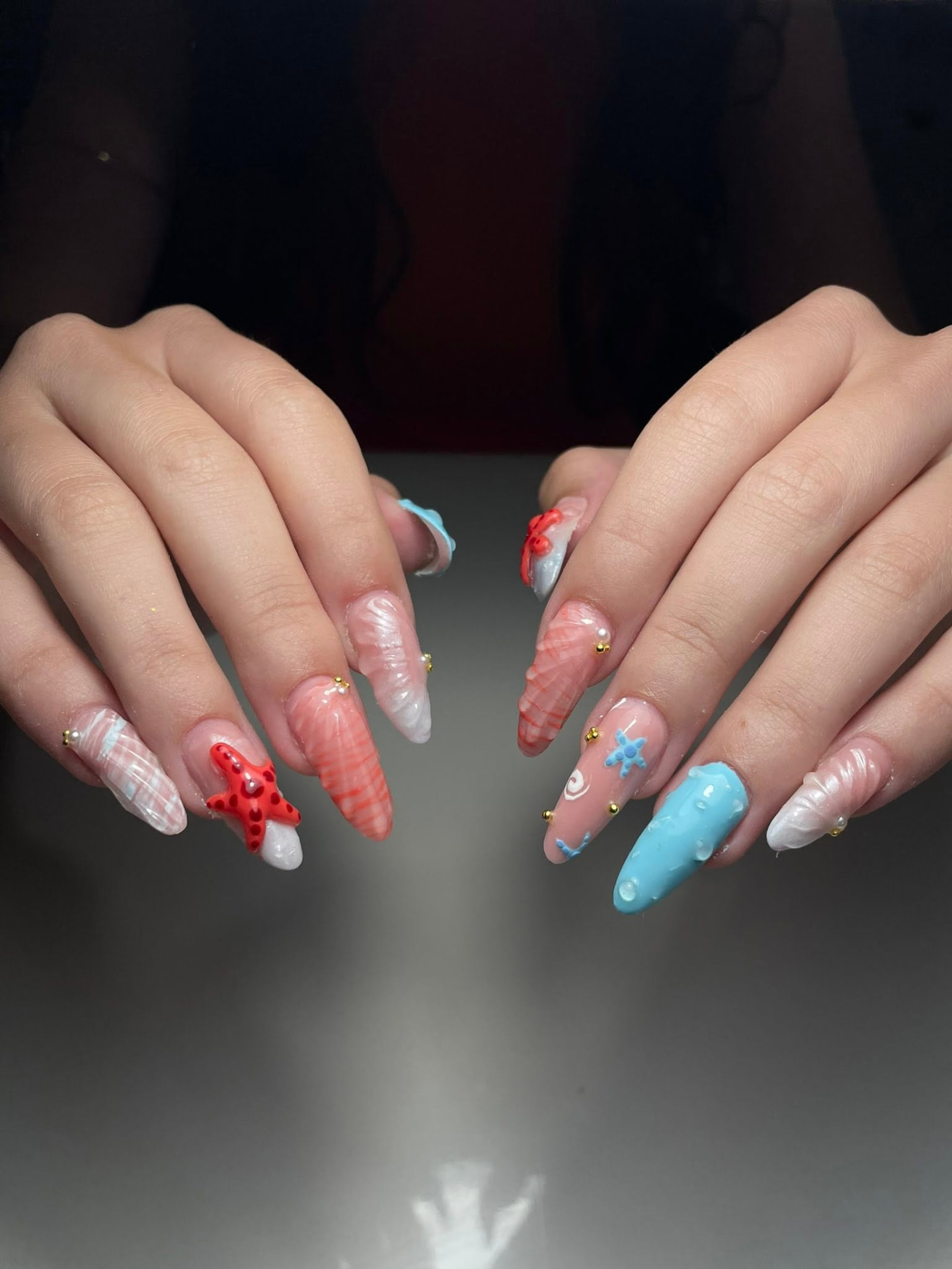 Nude almond nails with hand-painted blue flowers and gold detailing